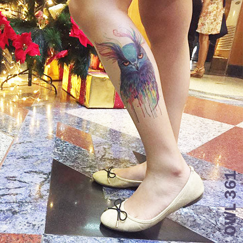 Woman's lower leg with temporary tattoo sticker in watercolored owl design.