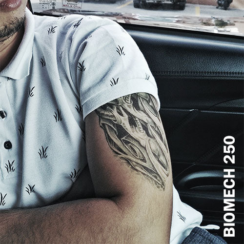 A man inside his car wearing a temporary tattoo sticker on his arm with biomechanical design.