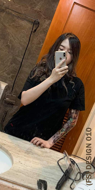 A woman with full sleeve temporary tattoo taking a picture of herself in the mirror.