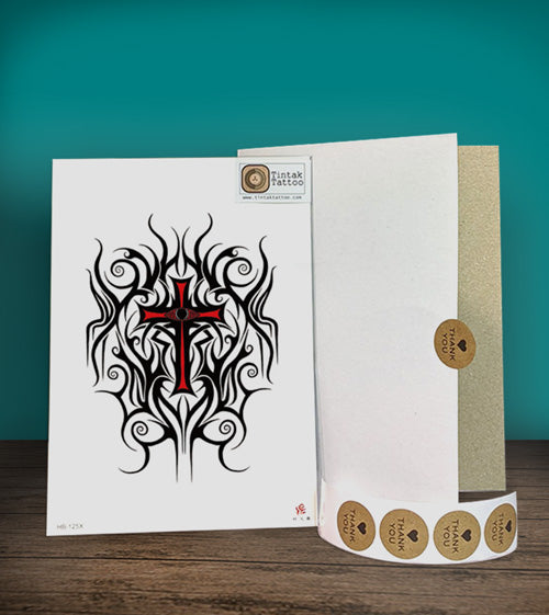 Tintak temporary tattoo sticker with tribal cross design, placed on a wooden table beside its packaging.