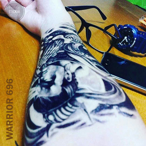 Warrior temporary tattoo sticker placed on a man's arm on top of a wooden table.