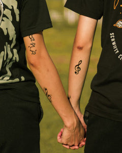 Music temporary tattoos with Gclefs on the arm of a man & a woman.