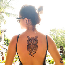 Load image into Gallery viewer, Woman on the beach with owl temporary tattoo on her back.