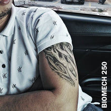 Load image into Gallery viewer, A man inside his car wearing a temporary tattoo sticker on his arm with biomechanical design.