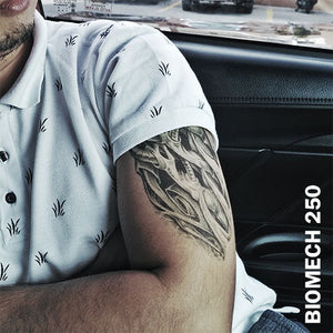 A man inside his car wearing a temporary tattoo sticker on his arm with biomechanical design.