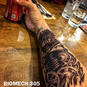 men's arm stretched on top of a wooden table with biomechanical temporary tattoo  sticker with gears and other machine parts