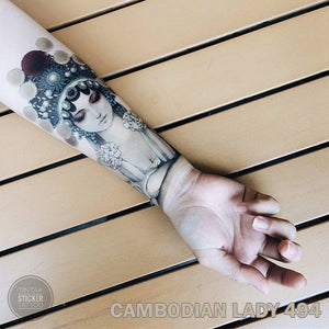 Woman's arm with cambodian lady temporary tattoo on top of a wood slats table.