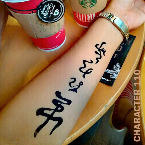 Woman's arm with chinese character temporary tattoo on top of a wooden table.