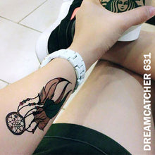 Load image into Gallery viewer, Woman&#39;s arm wearing a dream catcher temporary tattoo sticker and a watch while holding a starbucks paper cup.