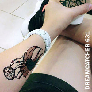 Woman's arm wearing a dream catcher temporary tattoo sticker and a watch while holding a starbucks paper cup.