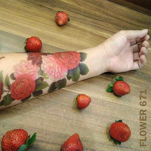 Peony flower temporary tattoo sticker on woman's arm on top of a wooden table with strawberries.