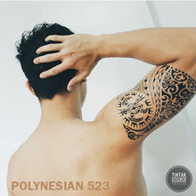 Load image into Gallery viewer, A man on his back, holding his head with his right hand with a polynesian temporary tattoo on his arm.