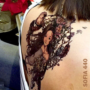 Woman's back with temporary tattoo sticker - animated girl inside the circled flowers with birds and feathers.